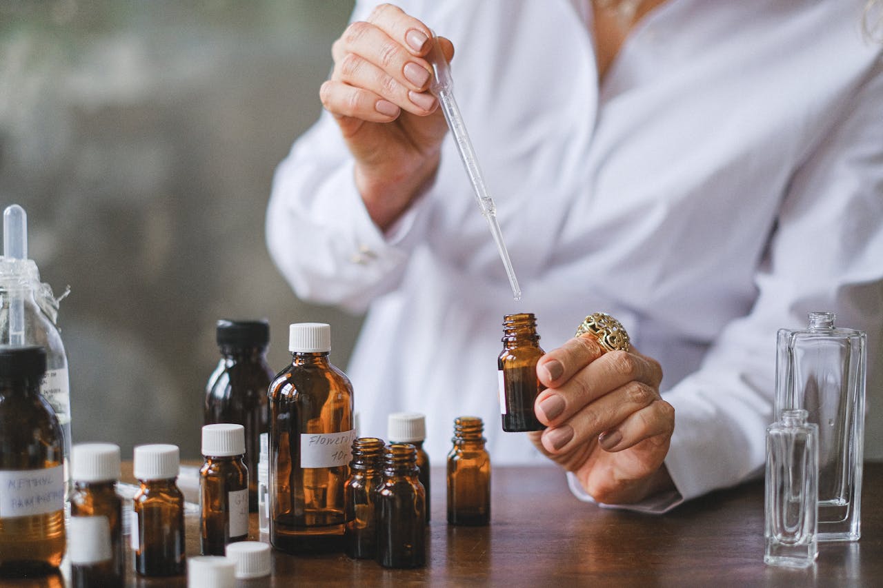 Close-up of hands handling amber glass bottles during an aromatherapy session.