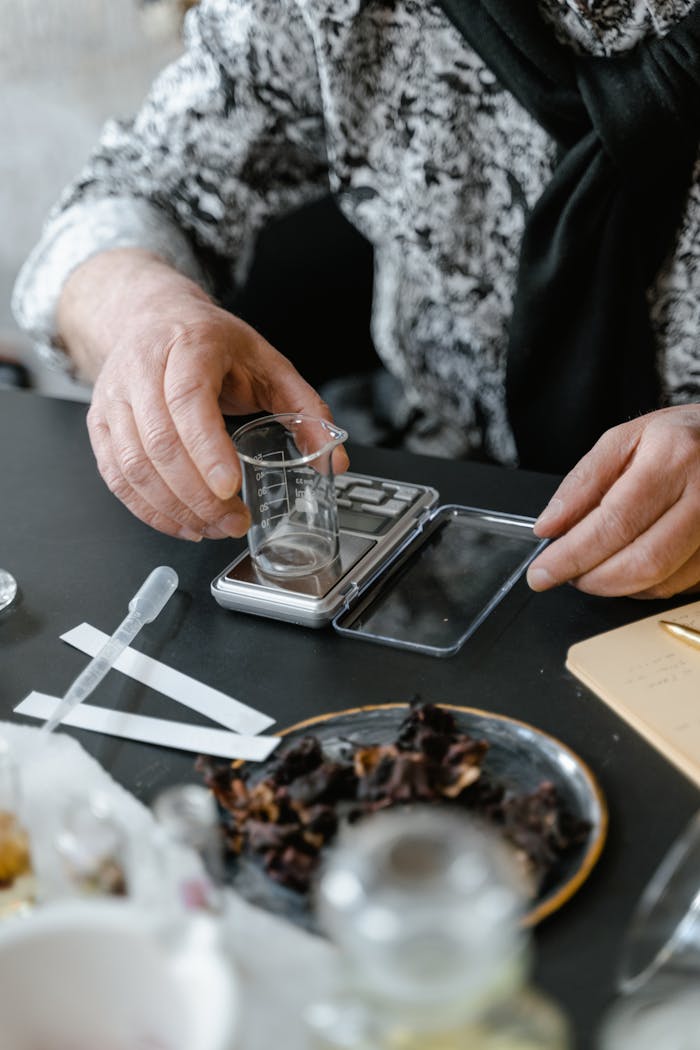 A detailed setup for crafting perfume using scales and fragrance materials indoors.