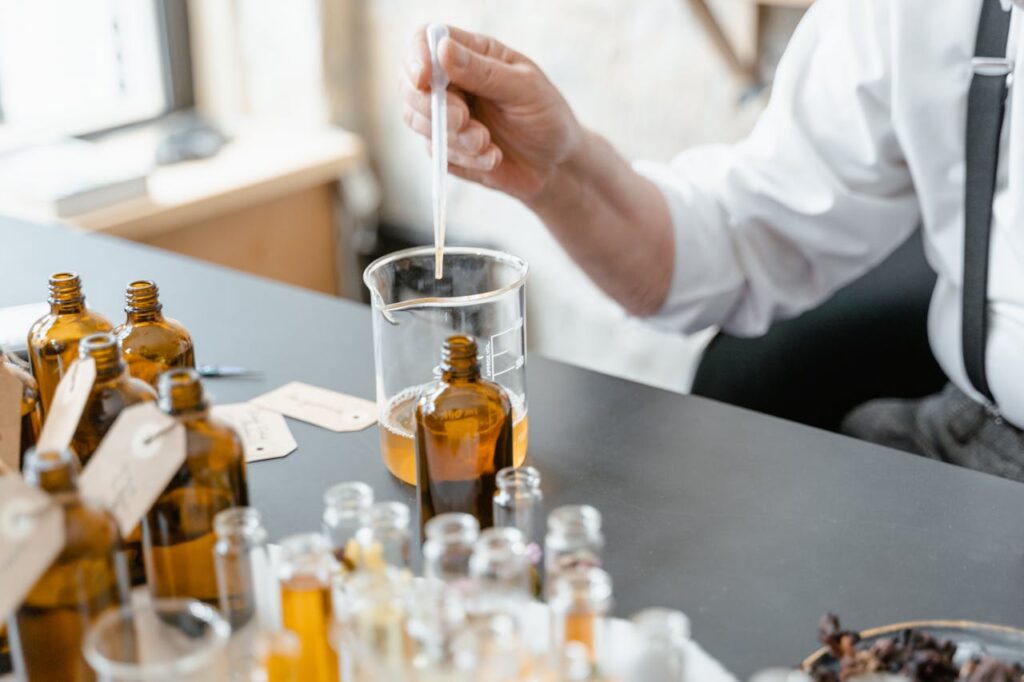 A person blends essential oils in glass bottles for aromatherapy indoors.