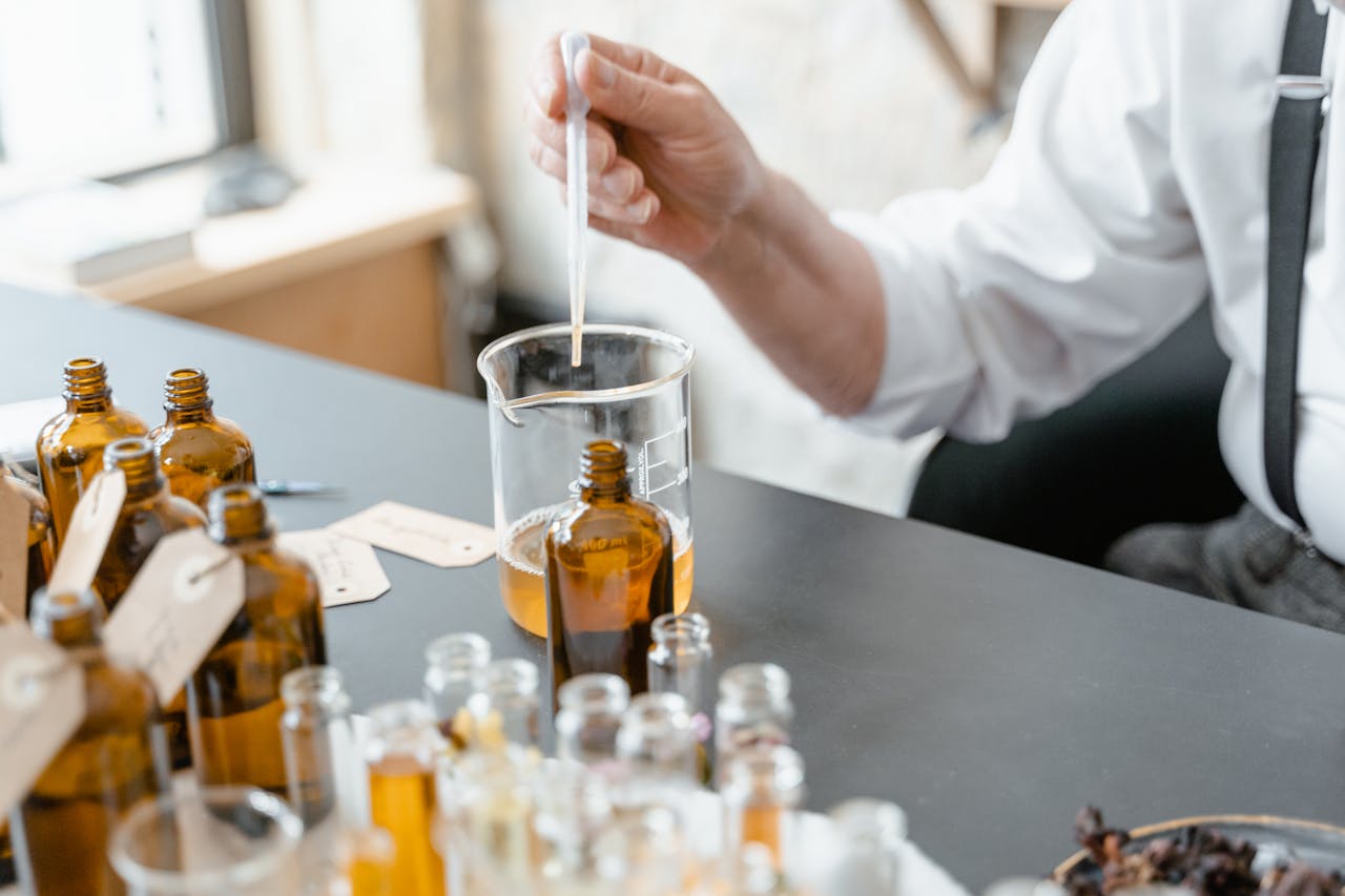 A person blends essential oils in glass bottles for aromatherapy indoors.